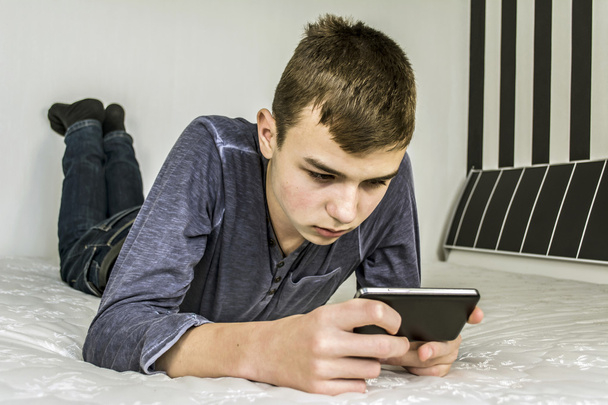 Teenager looks smart phone - Foto, immagini