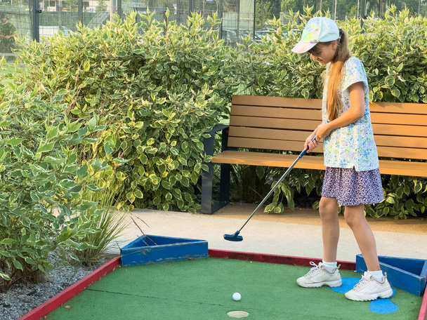 Little active child, cute toddler girl, playing miniature golf enjoying sunny summer vacation day outdoors in the park. High quality photo - Photo, Image
