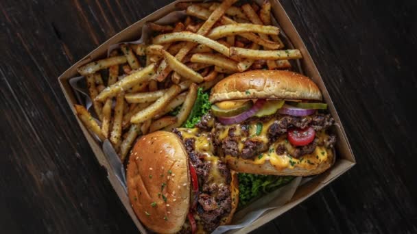 Close-up van twee sappige cheeseburgers met frietjes in een meeneemdoos, perfect voor een foodconcept. - Video