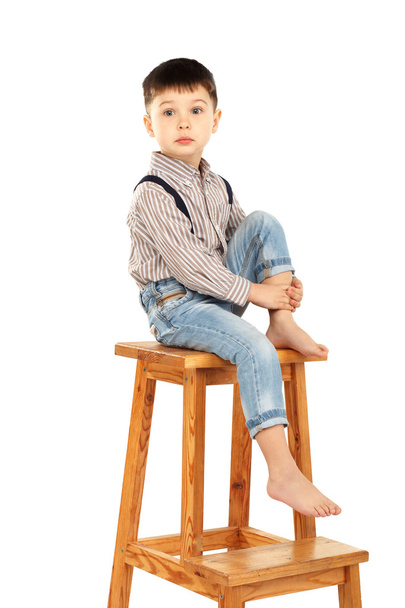 Portrait d'un drôle de petit garçon assis pieds nus sur un tabouret haut
  - Photo, image