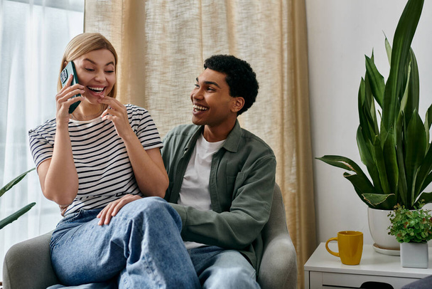 Молода пара, сміючись і насолоджуючись компанією, сидить в сучасній квартирі з рослиною на задньому плані. - Фото, зображення