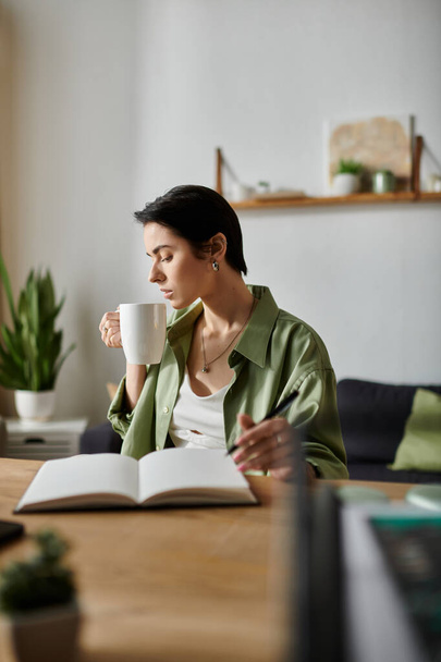 Μια γυναίκα κάνει ένα διάλειμμα από τη δουλειά της στο σπίτι, απολαμβάνοντας ένα φλιτζάνι καφέ. - Φωτογραφία, εικόνα