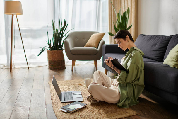 Жінка сидить на підлозі в домашньому офісі, працює на ноутбуці і робить нотатки. - Фото, зображення