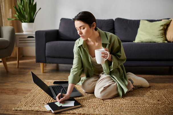 Frau arbeitet zu Hause am Laptop, nippt am Kaffee und schreibt. - Foto, Bild