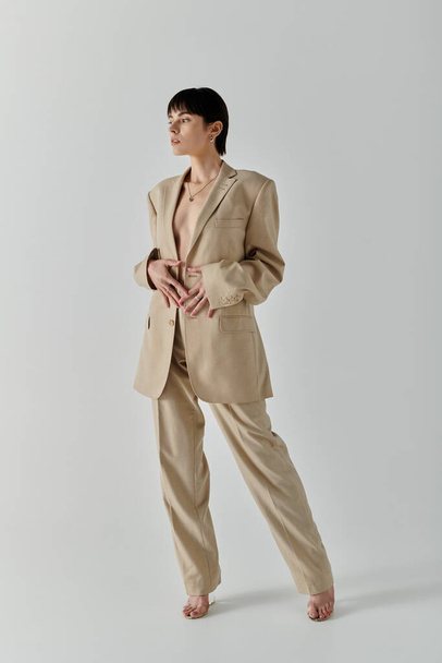 A woman in a beige suit poses confidently against a white backdrop. - Photo, Image
