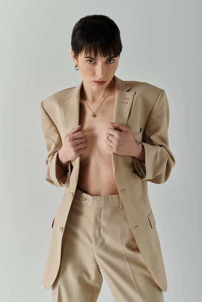 Une femme pose en toute confiance dans un costume bronzé sur fond blanc. - Photo, image