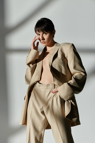 A woman wearing a beige suit poses against a white backdrop. - Photo, Image