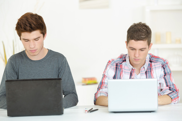 Dos estudiantes masculinos usando computadoras portátiles
 - Foto, imagen