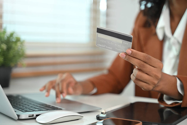 Primo piano donna d'affari in possesso di carta di credito e utilizzando il computer portatile per effettuare transazioni online. - Foto, immagini