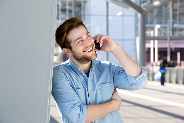 Счастливый молодой человек разговаривает по мобильному телефону
 - Фото, изображение