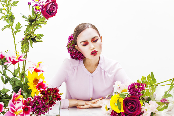 Kobieta portret siedzący przy stole z kwiatami - Zdjęcie, obraz