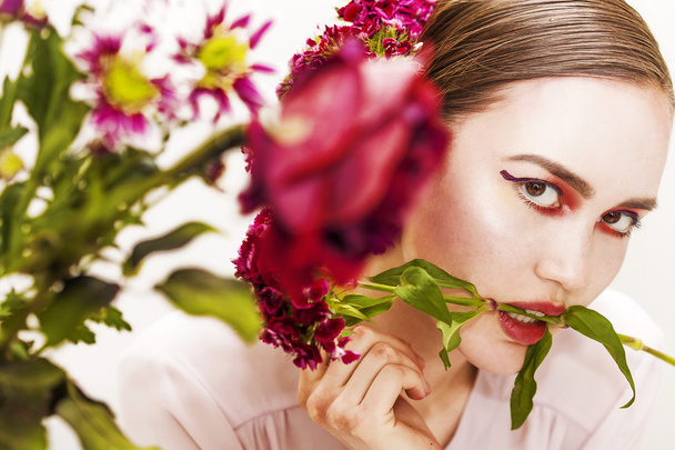 Woman beauty portrait biting flower branch and blurred flowers - Photo, image