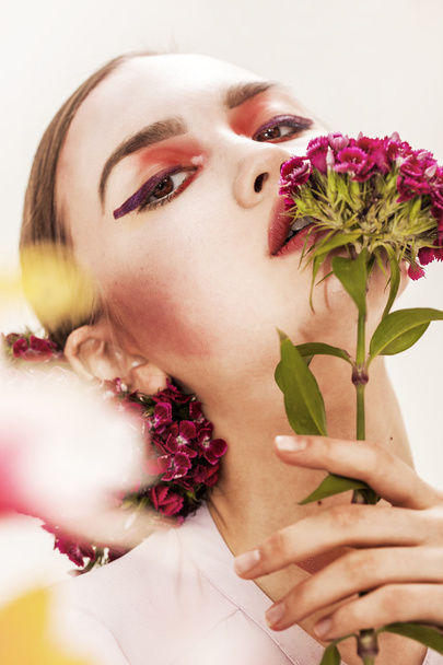 Hermosa chica retrato oliendo flores y mirando a la cámara
 - Foto, imagen