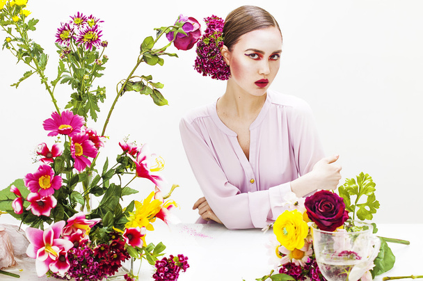 Beautiful woman sitting at the table with flowers - Foto, imagen