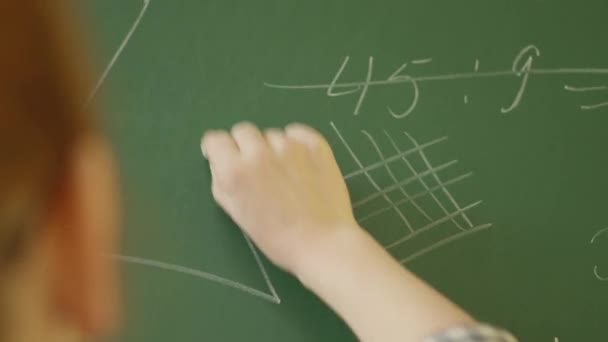 Вихователь, який дивиться ззаду, пише математичні формули на зеленій дошці. Послідовність зображень фіксує акт викладання та пояснення математичних понять у класі. - Кадри, відео