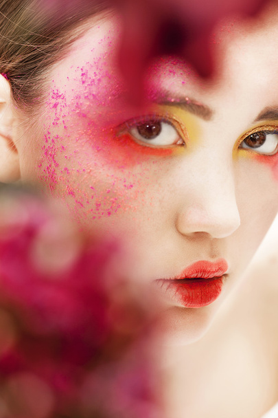 Girl closeup beauty portrait with blurred red flowers - Foto, imagen