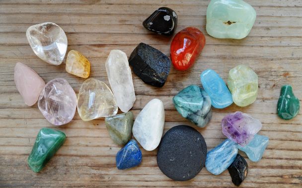 Diferentes pedras preciosas coloridas na mesa de madeira
 - Foto, Imagem