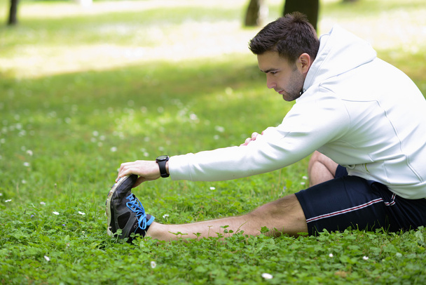 Handsome sportsman stretching outdoors - Zdjęcie, obraz