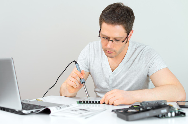 Mężczyzna technika lutowania lan routera przełącznik w jego miejscu pracy. - Zdjęcie, obraz
