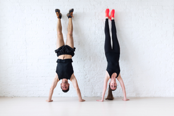 sportsmen woman and man doing a handstand against wall concept balance sport fitness lifestyle people - Фото, изображение