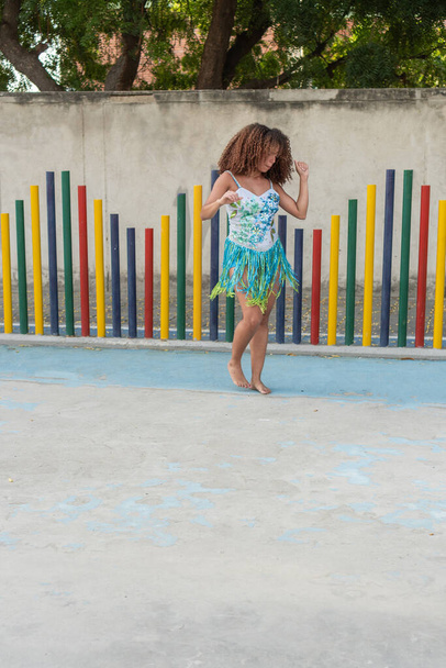 Mujer joven con el pelo rizado bailando juguetonamente en un vibrante vestido de flecos. - Foto, imagen