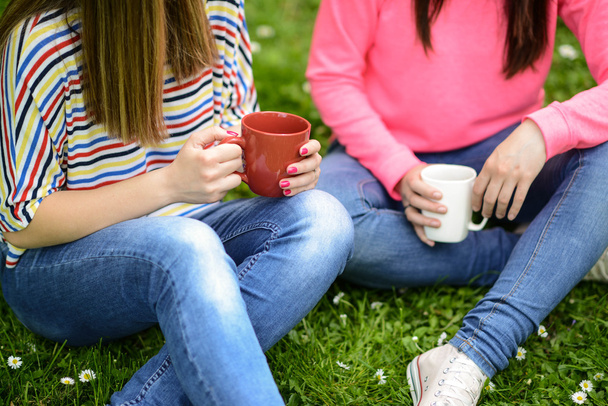 Young women drinking coffee at park and enjoying summer day - Foto, afbeelding