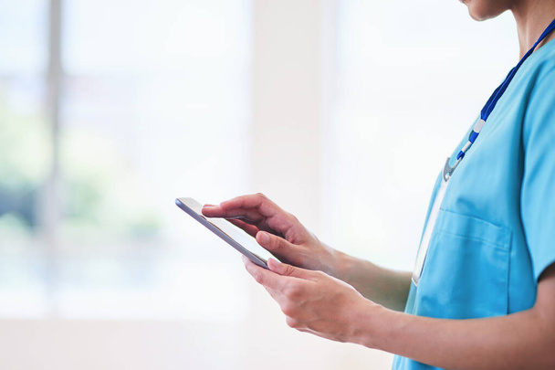Gros plan d'un professionnel de la santé en blouse bleue à l'aide d'une tablette numérique. Concept de technologie médicale moderne, de dossiers médicaux numériques et de milieux de soins professionnels dans les hôpitaux ou les cliniques. - Photo, image