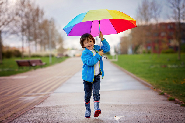 Cute little boy, walking in a park on a rainy day, playing and j - Valokuva, kuva