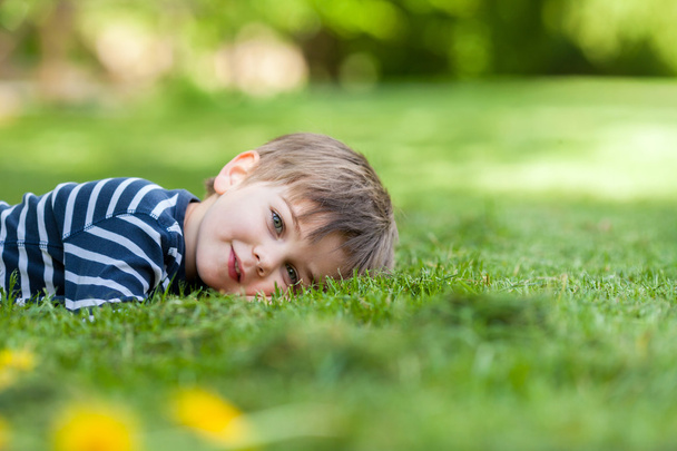 Smiling little boy, lying in the grass, smiling at the camera - Foto, Bild