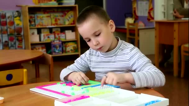 Boy in kindergarten closely engaged in a Board game. He's very serious, focused and passionate about a favorite pastime. It brings him pleasure. - Footage, Video
