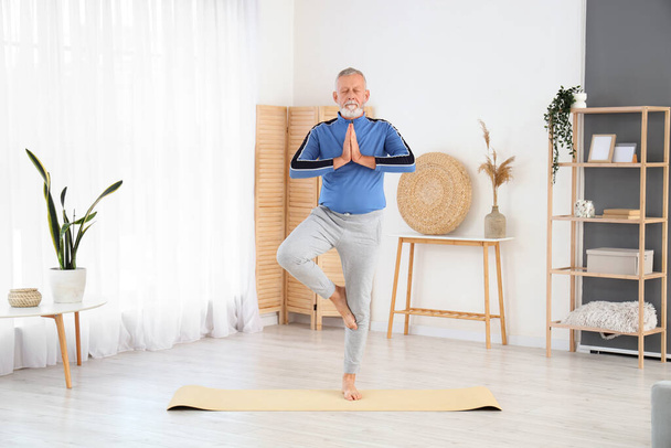 Sportovní starší muž dělá jógu na podložce doma - Fotografie, Obrázek