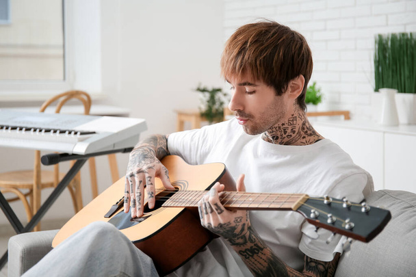 Cool tatuado joven tocando la guitarra en casa - Foto, Imagen
