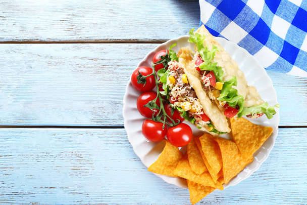 Tasty taco with nachos chips and vegetables on plate on table close up - Фото, изображение