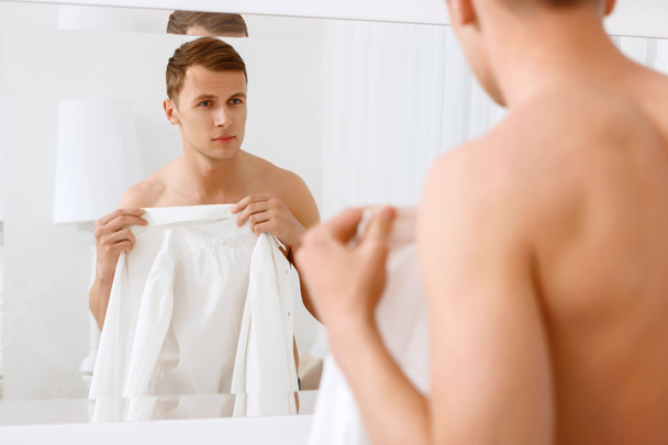 Man standing and covering himself with white shirt - Foto, imagen