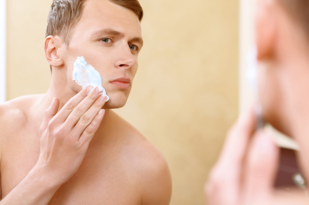 Oben ohne Mann Anwendung Mittel der Rasur im Gesicht - Foto, Bild