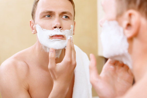 Hombre en topless aplicando medio de afeitarse en la cara
 - Foto, Imagen