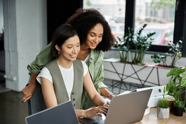 Duas mulheres, parceiras, colaborando em um laptop em um escritório moderno. - Foto, Imagem