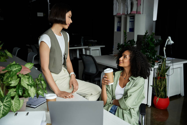 Két nő, irodai környezetben, megiszik egy csésze kávét, és együtt dolgoznak.. - Fotó, kép