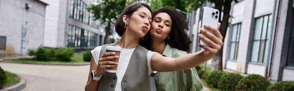 Zwei Frauen machen ein Selfie in einer urbanen Umgebung. - Foto, Bild