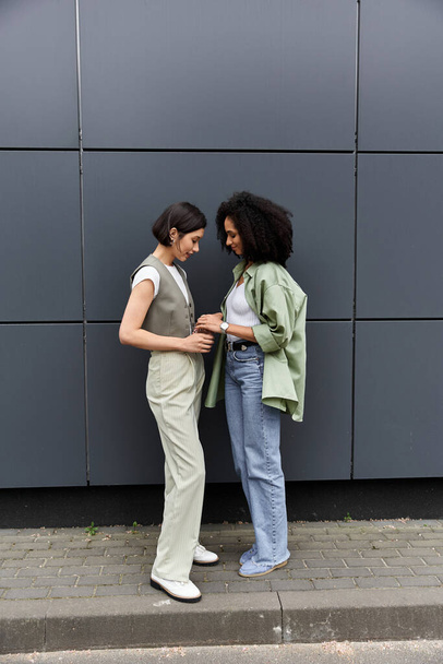 Due donne stanno fuori da un edificio moderno, godendo di un momento di connessione. - Foto, immagini