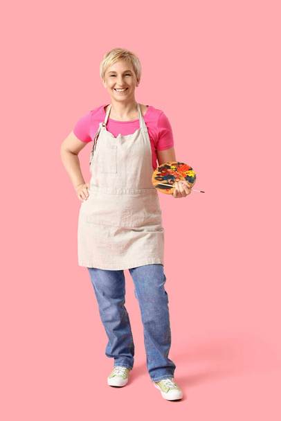 Ώριμη γυναίκα καλλιτέχνης με εργαλεία σε ροζ φόντο - Φωτογραφία, εικόνα