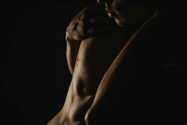 Крупним планом знімок захоплює деталі м'язового чоловічого торса з драматичним освітленням, що підкреслює м'язи і текстуру шкіри, виключаючи силу і мужність. - Фото, зображення