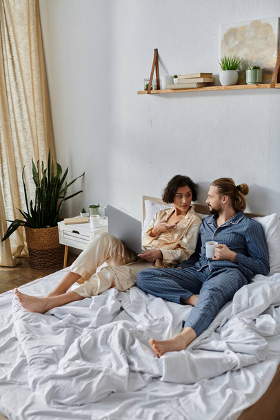 Milující pár relaxuje v posteli spolu, těší kávu a pomocí notebooku. - Fotografie, Obrázek