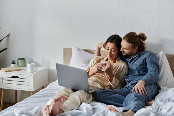 Couple relaxes in bed with coffee, browsing internet. - Photo, Image
