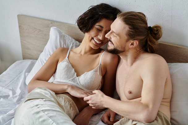 A couple shares a tender moment of laughter and affection in bed. - Photo, Image