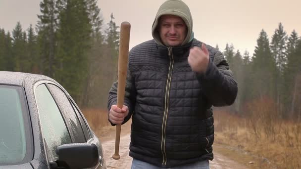 Агрессивный человек с бейсбольной битой возле машины в дождливый день
 - Кадры, видео