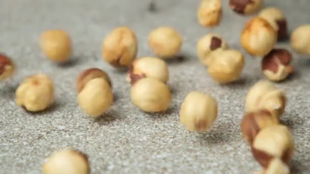 Scattering of peeled hazelnuts on a gray stone background, slow motion. - Footage, Video