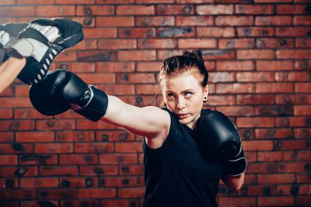 Woman wearing boxing gloves hitting training mits man is holding - Φωτογραφία, εικόνα