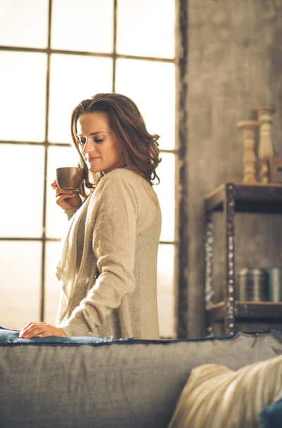 Brunette holding cup of coffee in loft - Фото, зображення