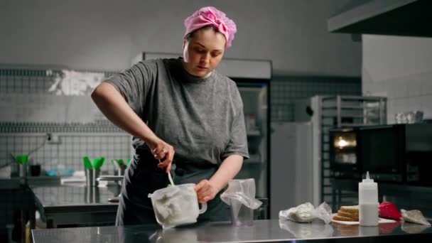プロのキッチンで女性ベイカーは,ペストリーバッグにクリームペーストを転送します - 映像、動画